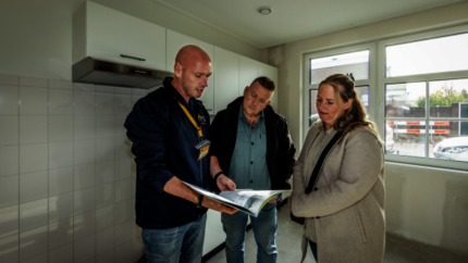 Verhuurmakelaar geeft uitleg aan nieuwe huurders in een nieuwbouw woning